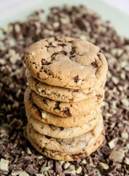 A stack of Andes Mint Chocolate Chip Cookies sitting on a bed of Andes Mint Chocolate Chips from The Merchant Baker