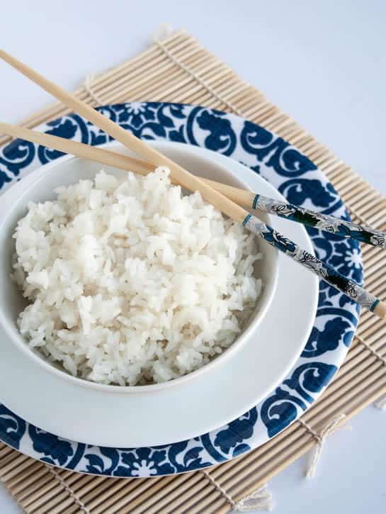 A closeup image of a bowl of Perfect White Rice with chopsticks from themerchantbaker.com