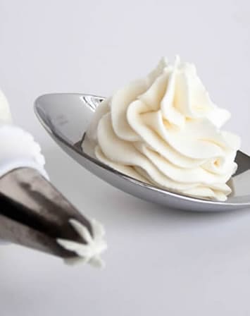Whipped Cream Cream Cheese Frosting on a spoon from themerchantbaker.com