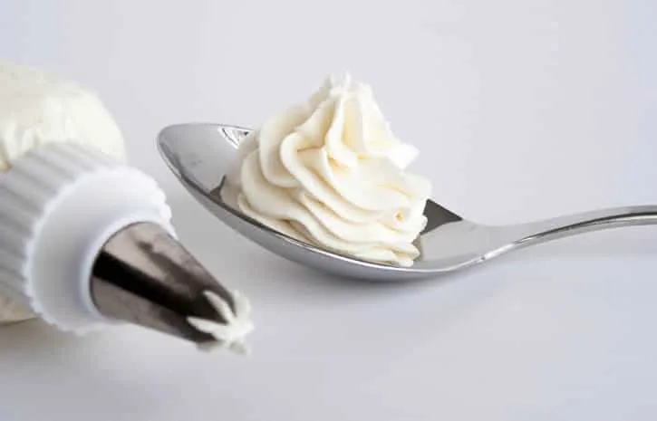 Whipped Cream Cream Cheese Frosting piped on a spoon from themerchantbaker.com