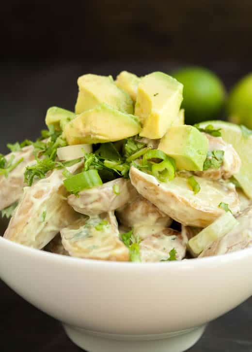 A closeup photo of Roasted Potato Salad with Avocado Lime Dressing topped with avocado from themerchantbaker.com