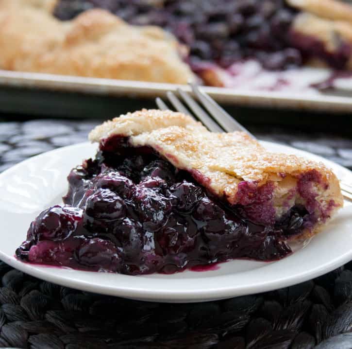 A slice of Blueberry Galette being served on a plate from themerchantbaker.com