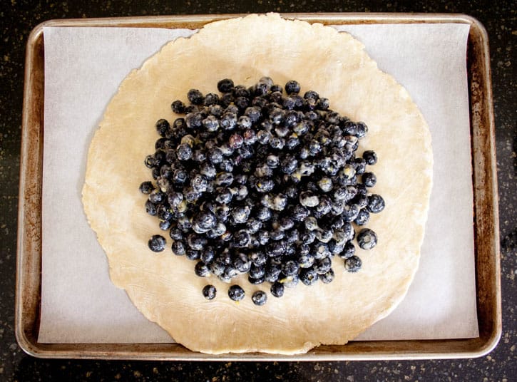 Raw dough for Blueberry Galette with blueberries on a baking tray ready to be folded from themerchantbaker.com