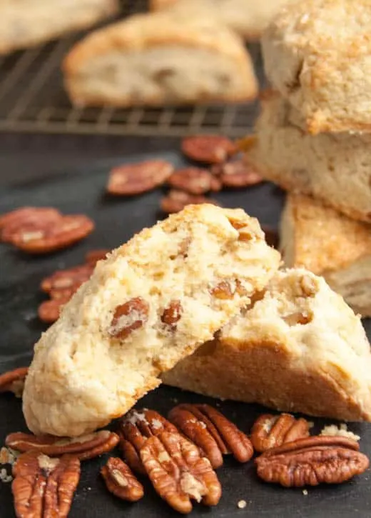 A Brown Sugar Butter Pecan Scone broken in half to display the inside texture and baked in pecans from themerchantbaker.com