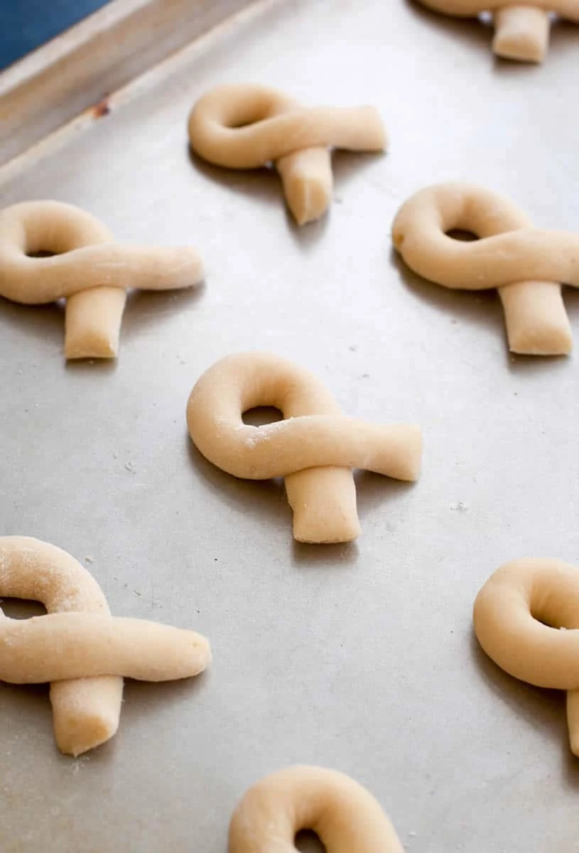 Uncooked Eggnog Kringla dough strips twisted on a baking sheet by themerchantbaker.com