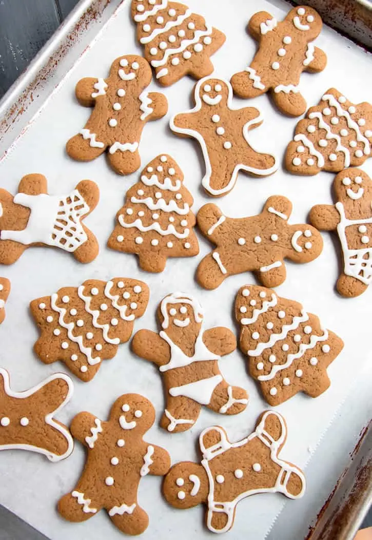 Soft Gingerbread Men, trees and women Cookies with icing trimming on a baking tray by themerchantbaker.com