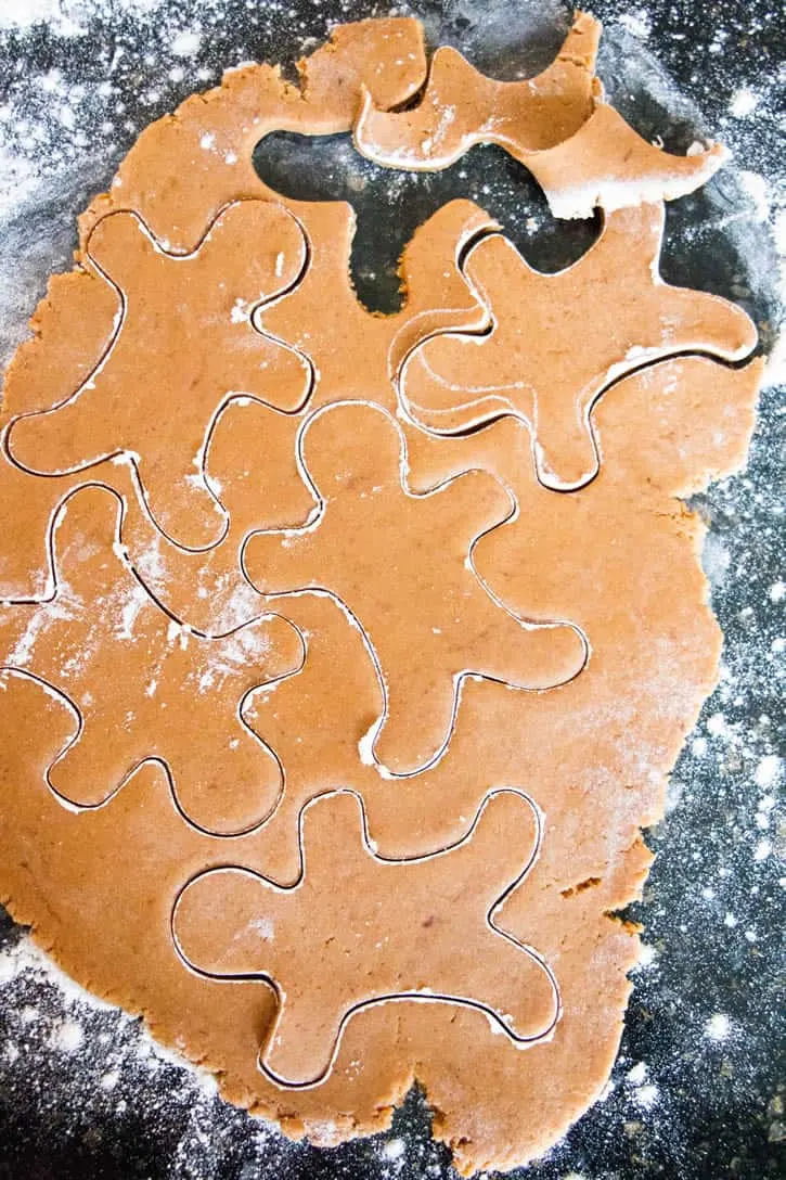 Rolled gingerbread cookie dough with cut-out gingerbread men to make Soft Gingerbread Cookies by themerchantbaker.com
