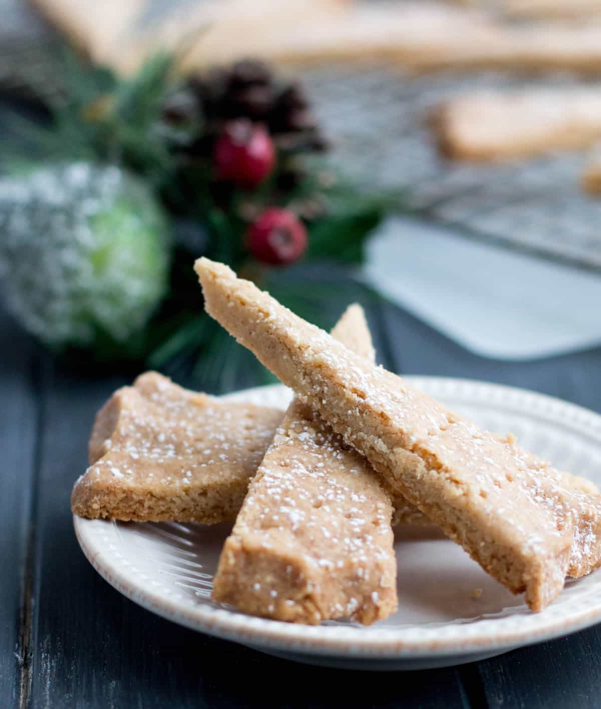 Three pieces of Spiced Shortbread on a white plate dusted with powdered sugar by themerchantbaker.com