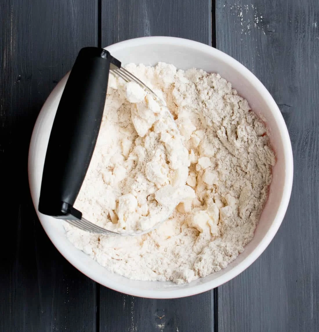 Cutting butter into flour in a white bowl to make Spiced Shortbread by themerchantbaker.com