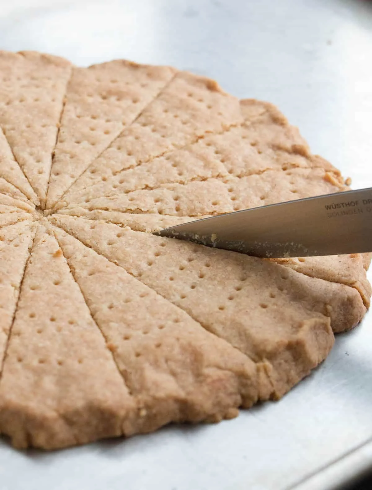 Cutting pizza like shapes from a freshly baked circle of Spiced Shortbread by themerchantbaker.com