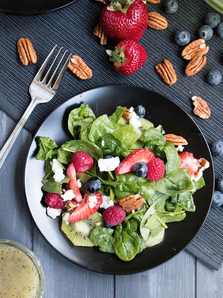 Kiwi Berry Spinach Salad with Honey Poppy Seed Dressing. Creamy goat cheese and candied pecans top this colorful salad with a dressing that's not too sweet! 
