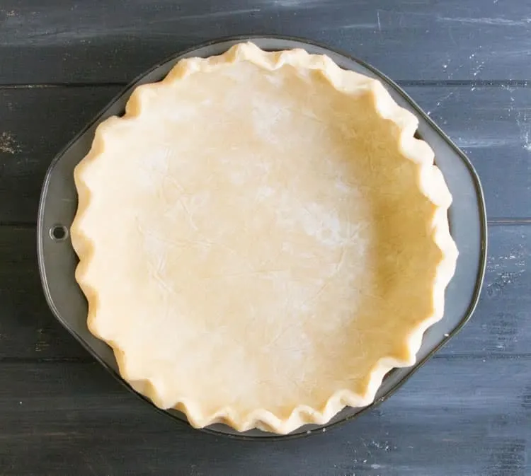 Easy All Butter Pie Crust in a pie pan fluted and ready for baking from themerchantbaker.com