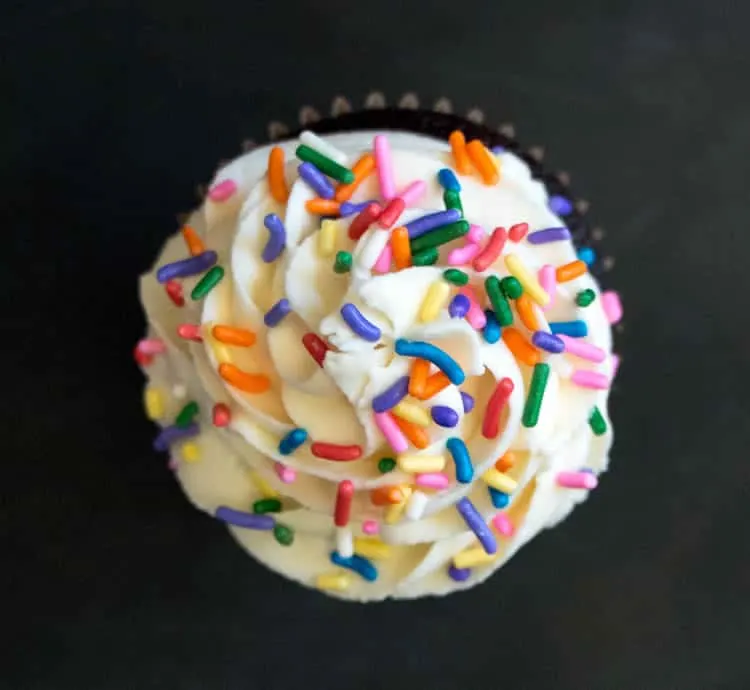 Whipped Cream Cream Cheese Frosting on a cupcake with sprinkles from themerchantbaker.com