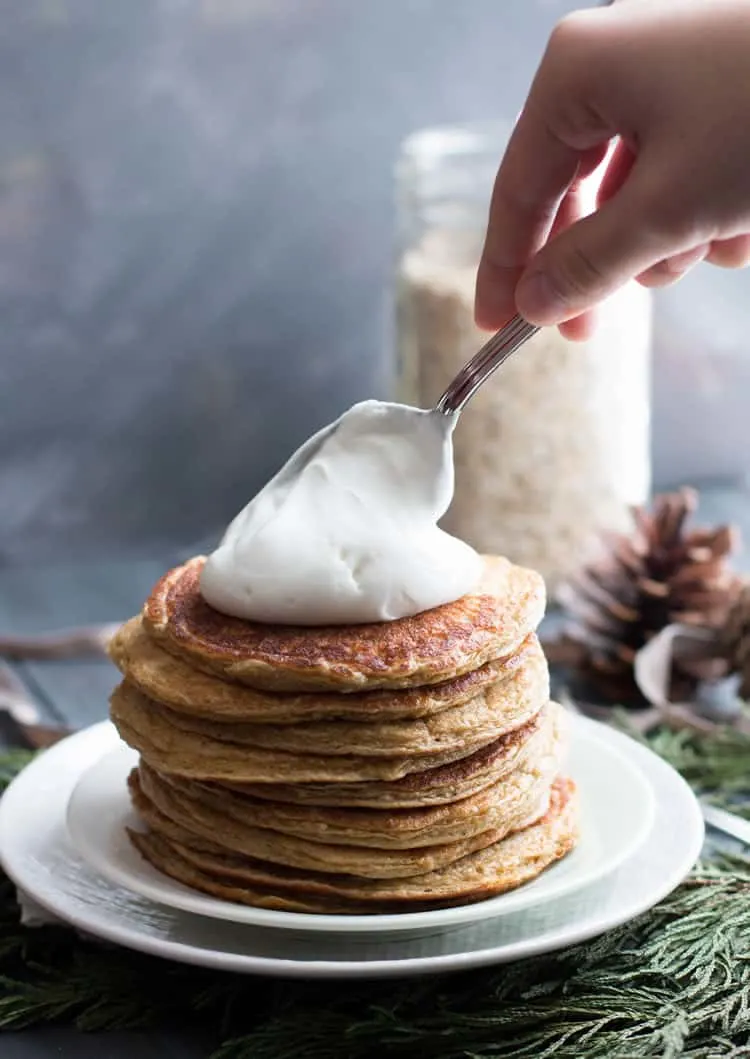 Topping Oatmeal Cottage Cheese Protein Pancakes with whipped cream from themerchantbaker.com