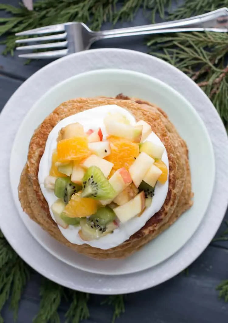 A closeup top view of Oatmeal Cottage Cheese Protein Pancakes topped with mixed fruit from themerchantbaker.com