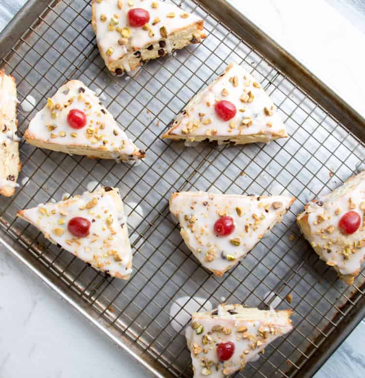 Chocolate Chip Ricotta Cannoli Scones are deliciously rich with butter and ricotta cheese, covered in a thin cherry vanilla glaze, then sprinkled with chopped pistachios and cherries!