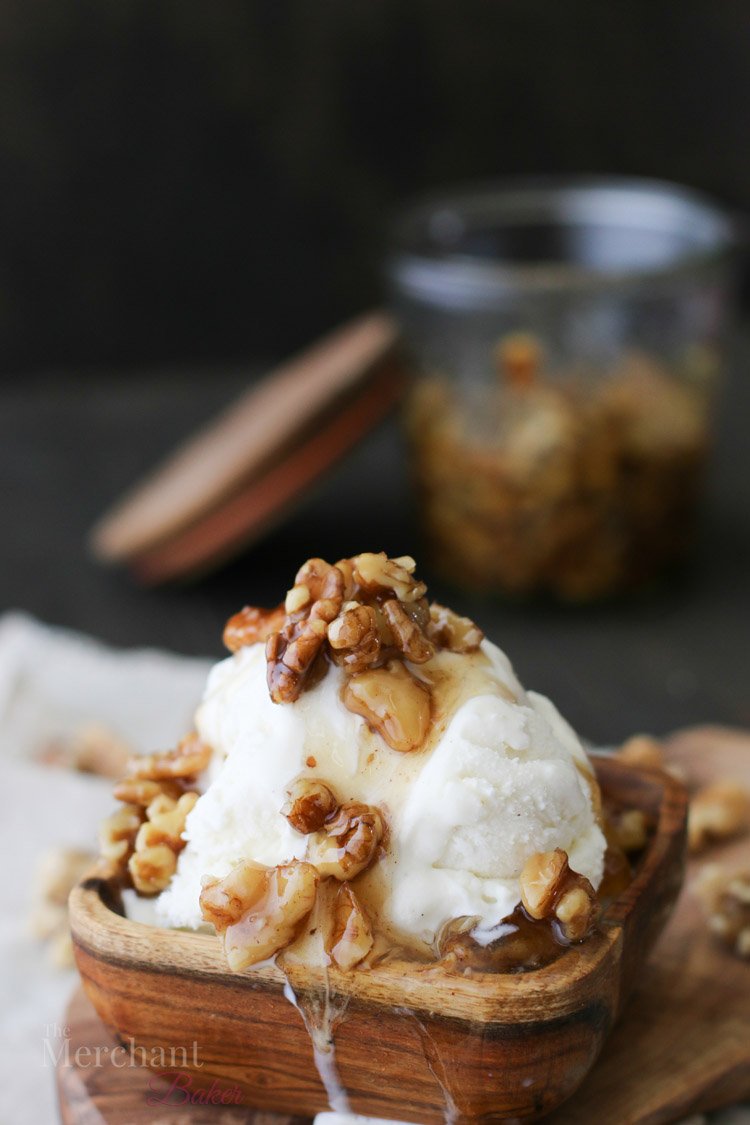 Scoop of vanilla ice cream in a wooden bowl topped with walnut syrup