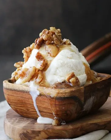 Scoop of vanilla ice cream in a wooden bowl topped with walnut syrup from themerchantbaker.com