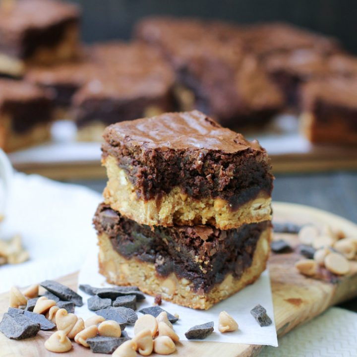 A two stack of Peanut Butter Blondie Brownies with chocolate chips and a bite taken from themerchantbaker.com