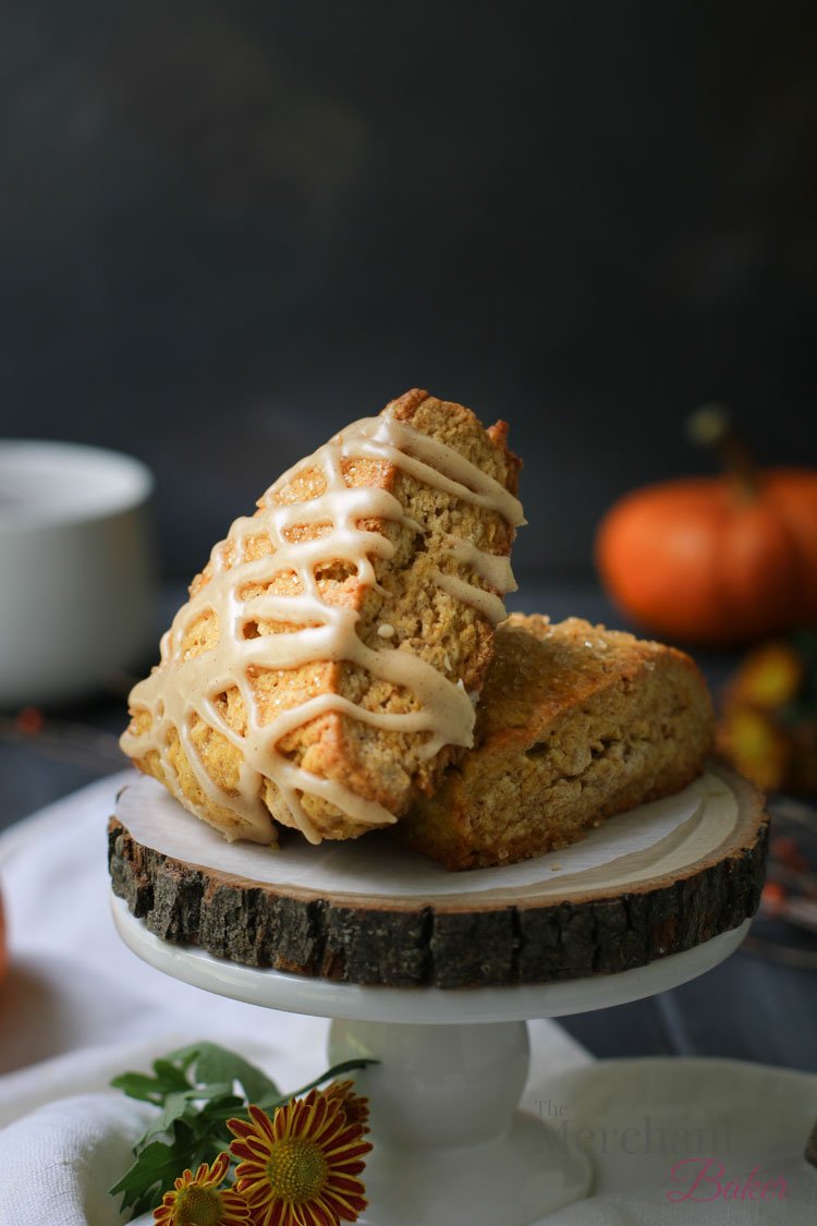 Two of the best pumpkin scones displayed on a raw wood slab by themerchantbaker.com