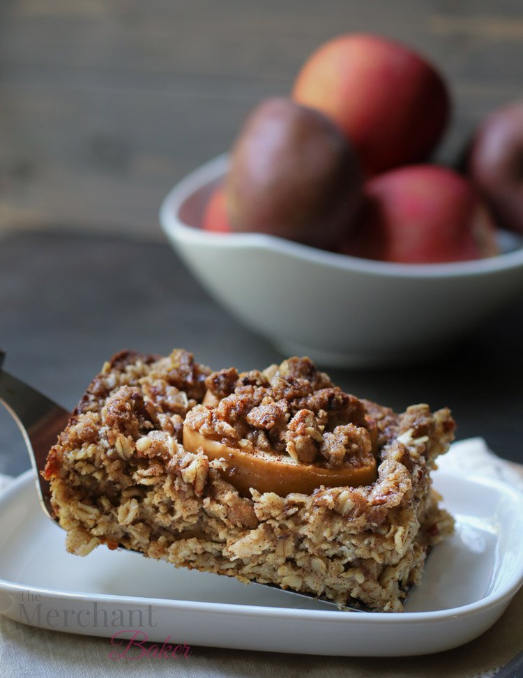 Side photo of a slice of Baked Apple Oatmeal being placed on a dish by themerchantbaker.com