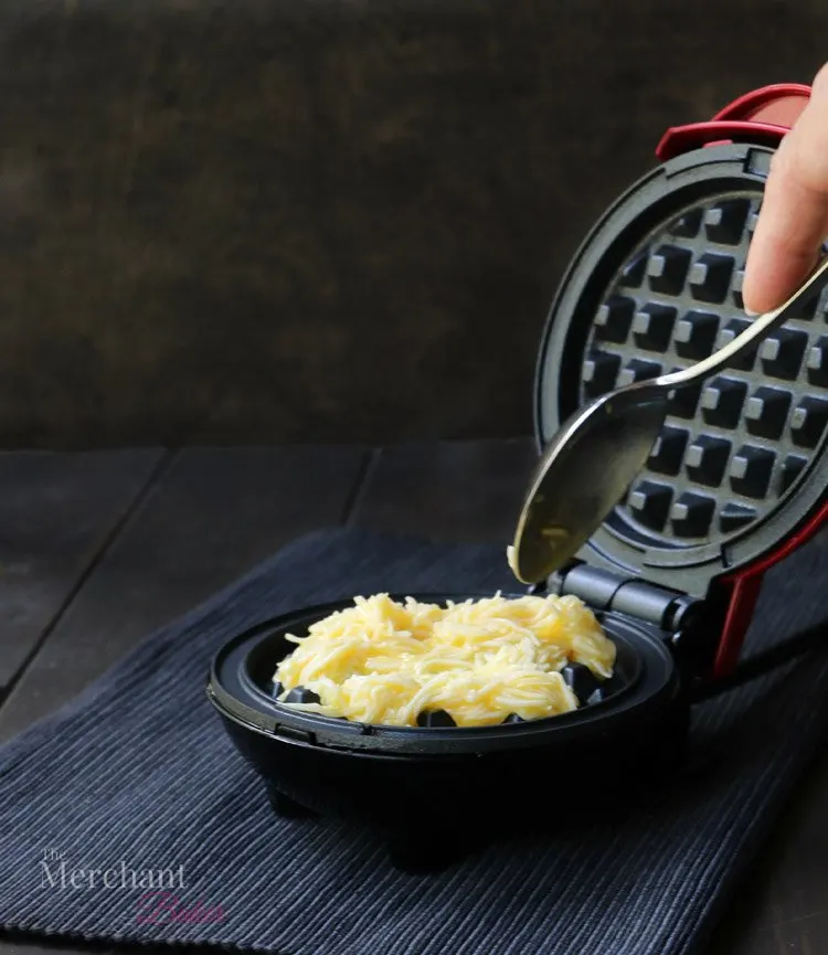 Pouring egg and cheese mixture into a chaffle maker. How to make Chaffles by themerchantbaker.com