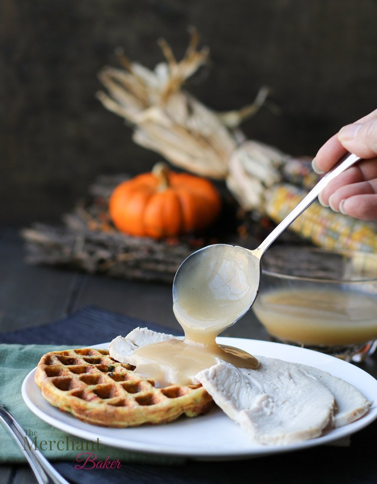 Pouring gravy over slices of turkey and Low Carb Stuffing Chaffles on a plate by themerchantbaker.com