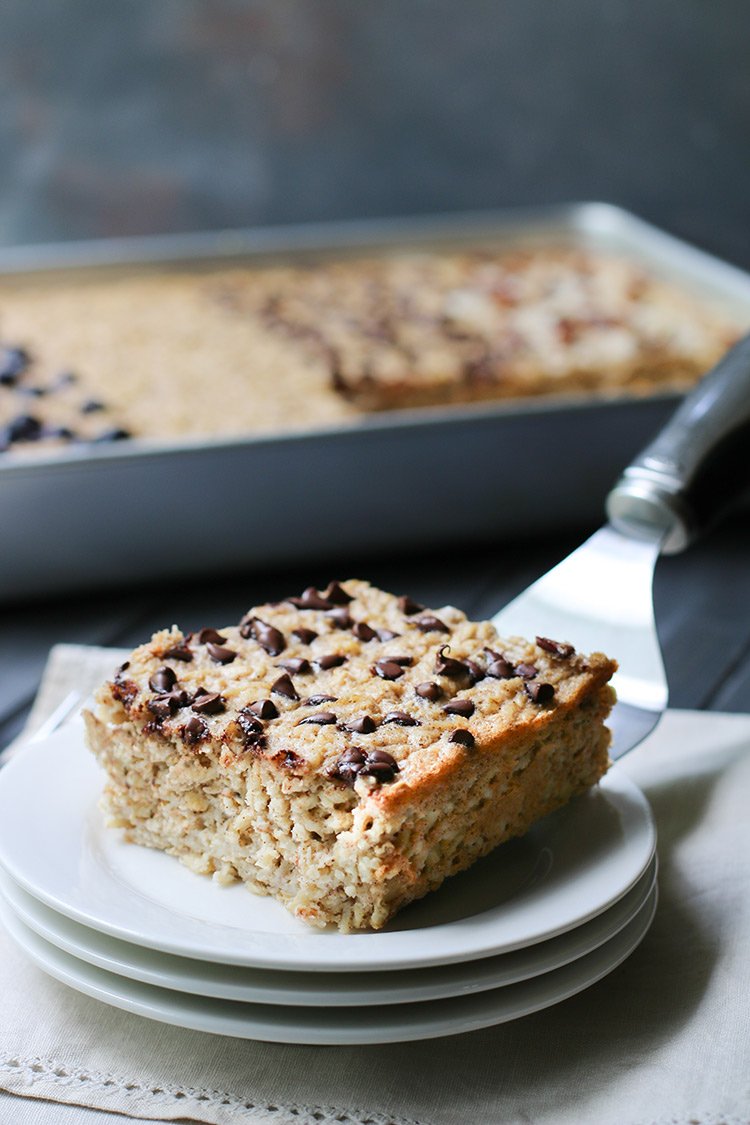 Square of baked oatmeal with chocolate chips being placed on a plate.