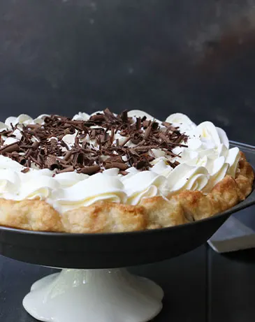 Side view of chocolate cream pie on a cake pedestal
