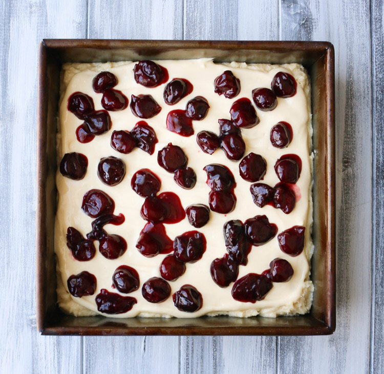Cooked cherries scattered over the top of cheesecake batter
