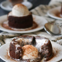 Spicy Molten Chocolate Lava Cake on a white plate with molten lava center oozing out and vanilla ice cream melting on top