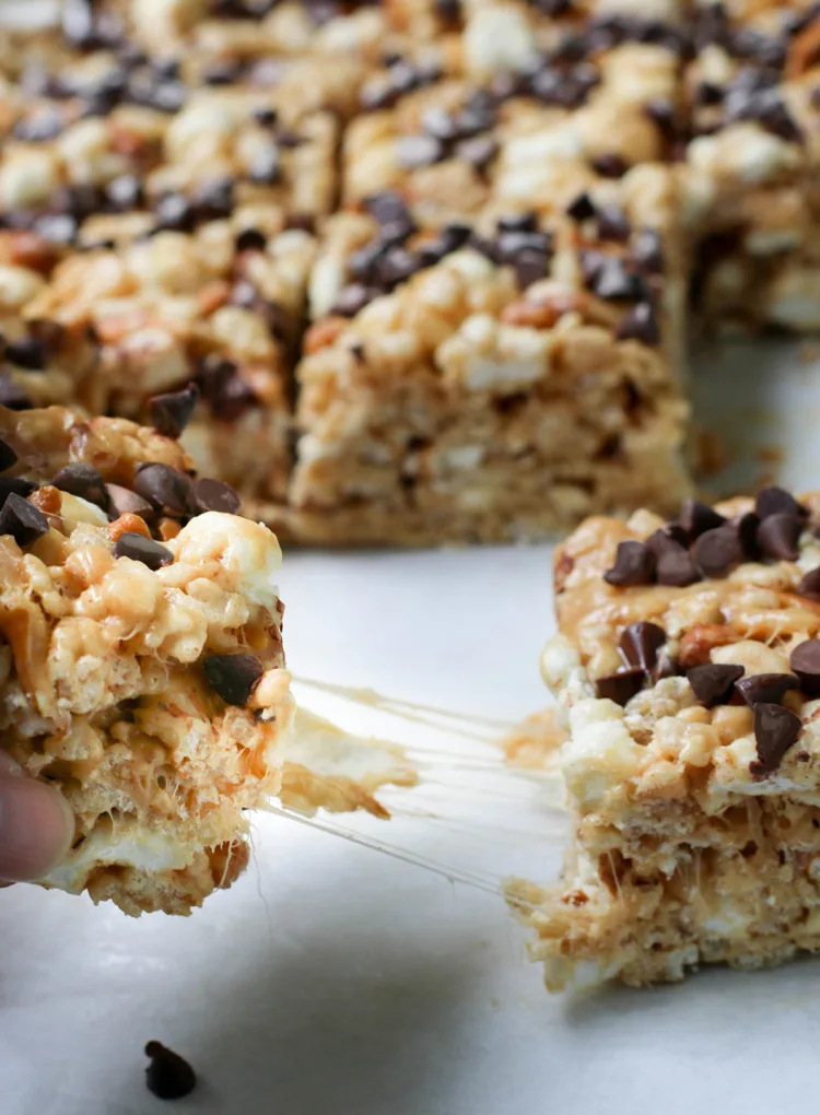 close up of pulling one peanut butter pretzel rice krispie treat away from another with a gooey marshmallow pull in between them