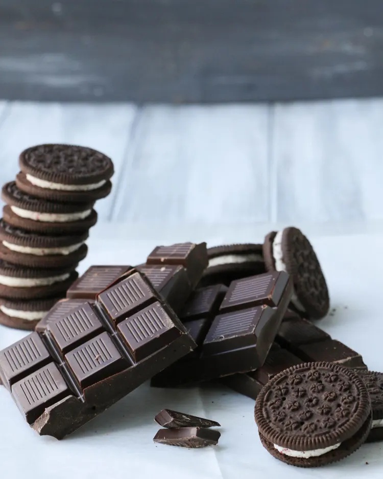 Bars of dark chocolate posed with stacked peppermint cookies.
