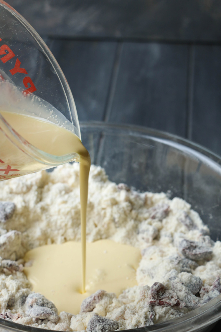 Egg and heavy cream mixture being poured into dry ingredients.