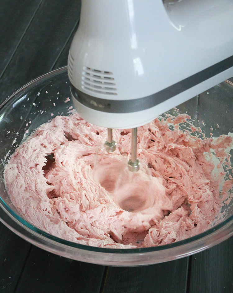 Strawberry Whipped Cream Cream Cheese Frosting being mixed in a glass bowl