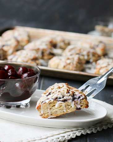 Placing a Cherry Almond Scone on to a plate with a spatula.