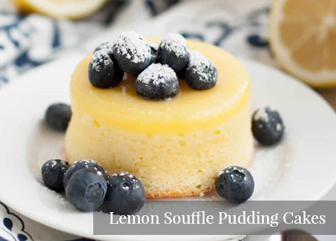 Lemon Souffle Pudding Cakes topped with blueberries and powdered sugar.