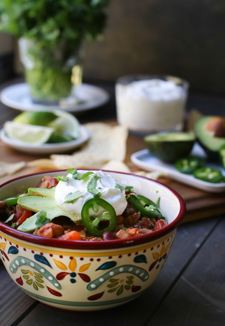A bowl of Turkey Chili topped with slices of avocado, jalapeno, sour cream and cilantro.