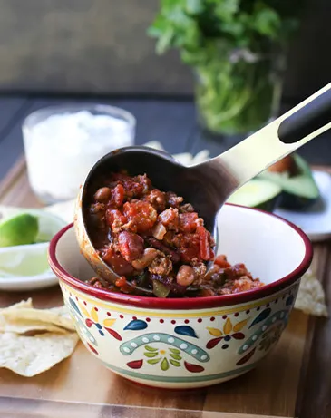 Pouring Turkey Chili into bowl from ladle.